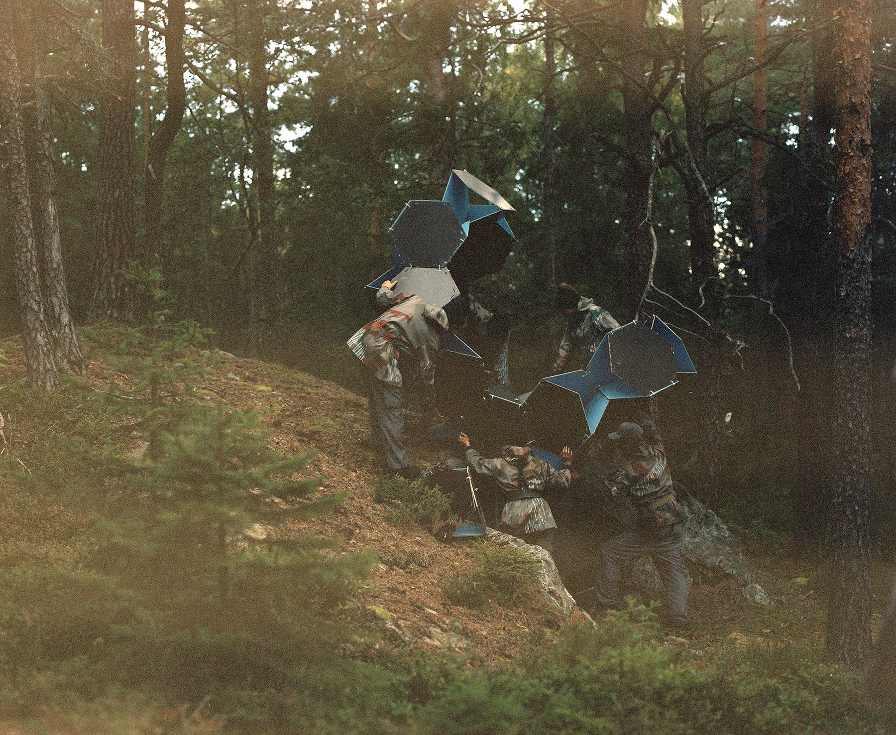 Figures carrying hexagonal panels up a forested slope, Borgåsen