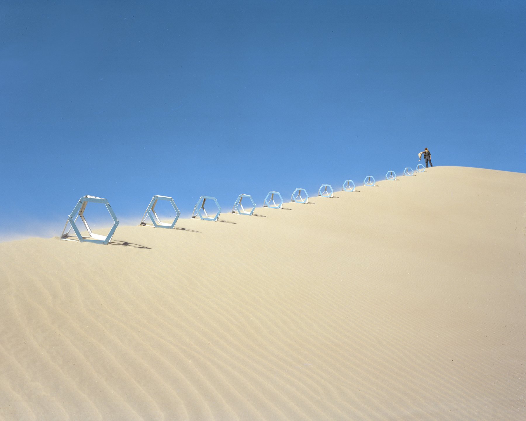 Line of blue cube markers descending a sand dune at Glamis
